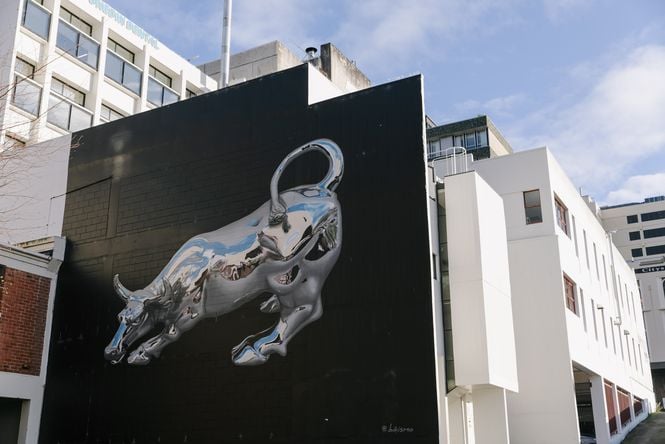 A silver bull painted on to a black wall.